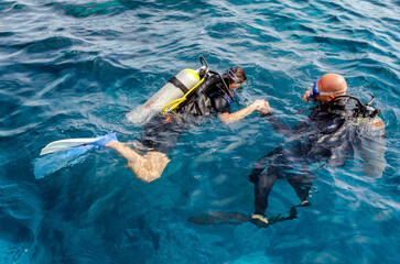 diving instructor holding a disciple's hand in blue water © Sofiia