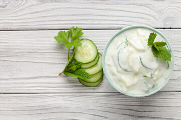 Indian Fresh sauce called Raita with herbs, dahi and sliced cucumber in a bowl on the table. Top view