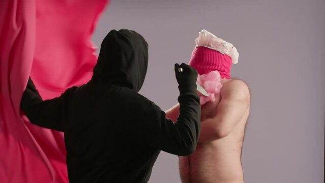 A maniac with a knife pulls back the shower curtain, intending to attack a man. A halfnaked man in a pink ski mask, a waterproof hat fights off the maniac, drives him away, closing the shower curtain.