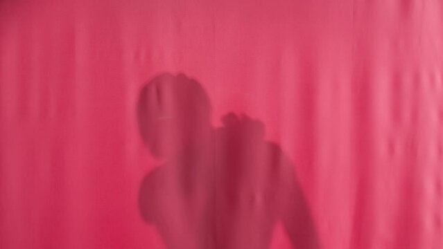 Silhouette of a man washing with a loofah in a shower behind a pink curtain. A man pulls back the curtain, covers his body in shock, throws a washcloth, and hides behind the curtain. Peeping while