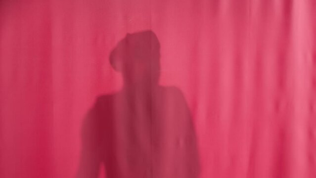 Silhouette of a man washing with a loofah in a shower behind a pink curtain. The man pulls back the curtain, cries out in fright and surprise, closes the curtain. Peeping in the shower.