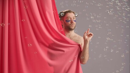 Seminude man covered by pink shower curtain bursting soap bubbles swirling around him. Funny man...