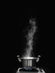 steam over cooking pot in kitchen on dark background.
