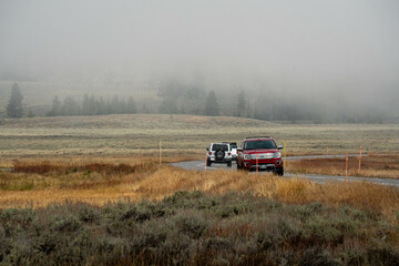Fototapeta premium Car driving in North american endless asphalt mountain road in autumn, Yellowstone National Park, Wyoming, USA 