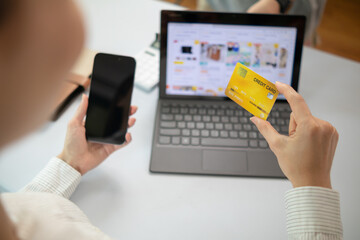 Young woman is shopping online through mobile application by paying with her credit card Convenience of paying through shopping online. Concept of online shopping and spending through credit card.