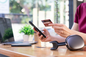 Young woman is shopping online through mobile application by paying with her credit card Convenience of paying through shopping online. Concept of online shopping and spending through credit card.