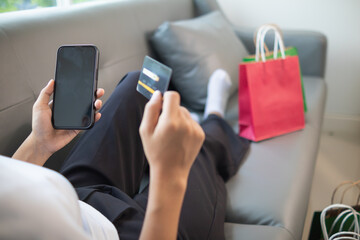 Young woman is shopping online through mobile application by paying with her credit card Convenience of paying through shopping online. Concept online shopping and spending through credit card.