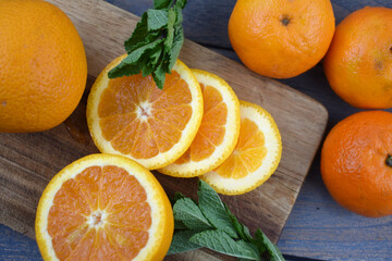Slices of oranges, tangerines, citrus fruits, clementines, manderins on cutting board with mint