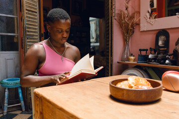 young haitian woman with short hair at home sitting in living room reading comfortably
