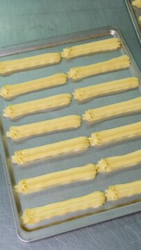 A pastry chef makes eclairs in a bakery. eclairs are baked in the oven. eclair production process. pastry bag with dough	