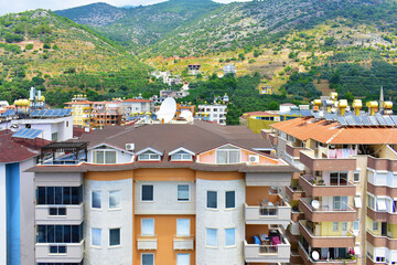 City view of multi-storey modern cottages on a mountainside with trees on a summer day. Turkey, Alanya, July 2023.