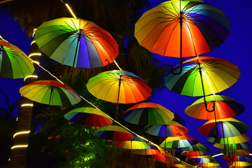 Row of hanging colorful umbrellas against the background of the evening sky