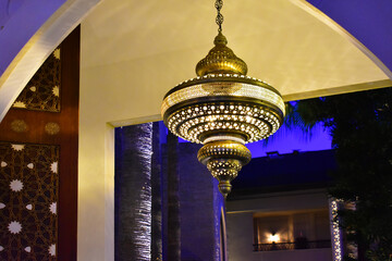 Large carved oriental chandelier and an Arabic-style interior. Evening light. 