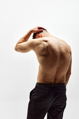 Fototapeta premium Round back. Shirtless young man with muscular relief body standing in pants isolated over white studio background. Health care. Concept of male beauty, body care, fitness, sport, fashion