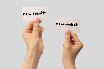 New mindset - new result  text on a card in a woman hand isolated on a grey background.