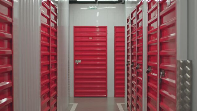 Zoom out dolly shot of unit with red steel door in corridor of self storage warehouse