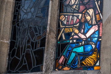 Von Sonne beleuchtetes Kirchenfenster mit Glasmalerei Maria mit Kind in der Krippe