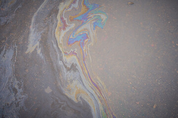 Obraz premium Close-up of an iridescent oil or gasoline spill on a wet asphalt, viewed from above.