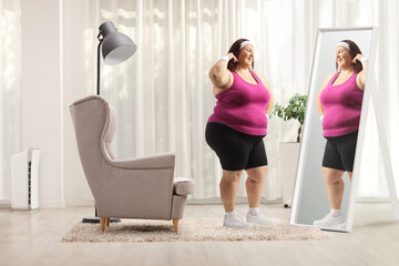 Fototapeta na wymiar Plus size woman in sportswear in front of a mirror at home