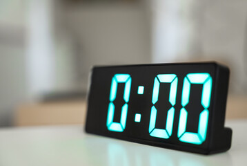 Close up of digital alarm clock at midnight time. Green numbers zero on a black screen. The start...
