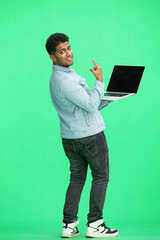 man on a green background. uses a laptop, back view