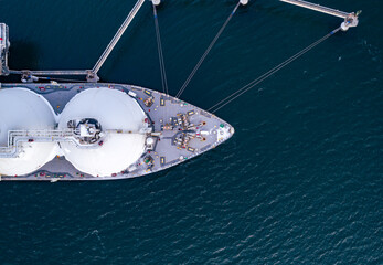 Aerial top down of Liquified Natural Gas LNG carrier moored to a small gas terminal. Top down view...