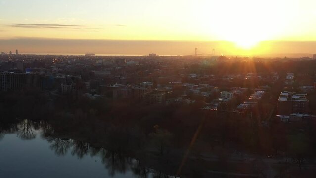 Slow aerial dolly in towards western Brooklyn over Prospect Park at golden hour