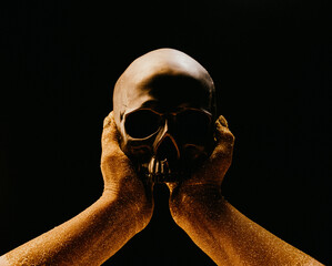 Hands with human skull on black. Golden sands, time concept. Symbolism, mortality