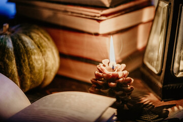 Old paper book, wooden windowsill.Cute cone candle, cozy nostalgic, retro allure