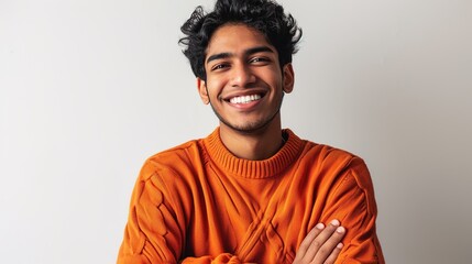 Young man wearing orange sweater over isolated white background happy face smiling with crossed arms looking at the camera