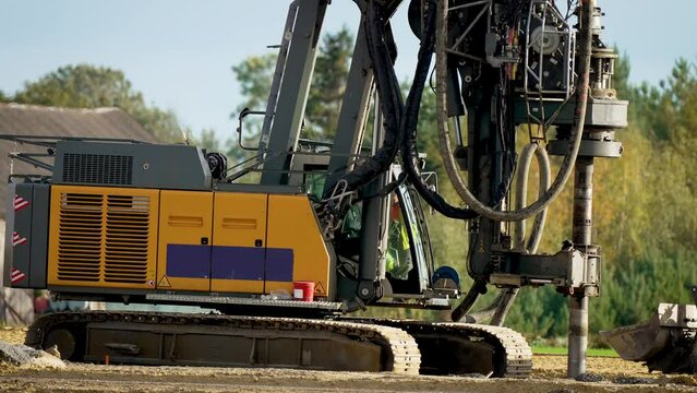 Machine lowers drill down. Drilling water wells. Digs holes in ground with drilling rig. Equipment for installing piles in ground heavy machines. Driving pillars work in laying foundation building