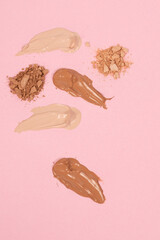 Various shades of foundation on a pink background, Makeup foundation cream strokes of different shades on skin tone color background 