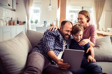 Happy family using tablet on the couch at home