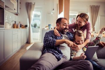 Happy family using tablet on the couch at home