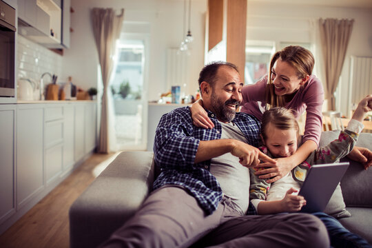 Happy family using tablet on the couch at home