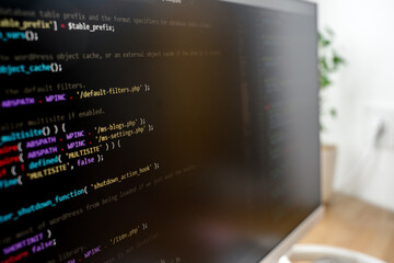 Html code on the screen of a white monitor standing on a wooden table with a keyboard, a coworking office. Selective focus. A beautiful programmer's workplace. St. Petersburg, Russia - Oct 28, 2023