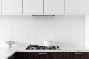 A kitchen detail with white and wood cabinets, decorations on the white marble countertop, and...
