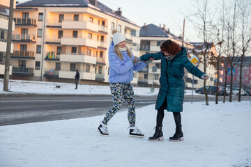 The girl wobbles while standing in the snow and a friend has to support her.