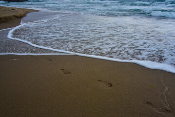 footprints in the sand and the waves washing them away symbolism of the ever-changing world of the perishability of people and the eternity of nature