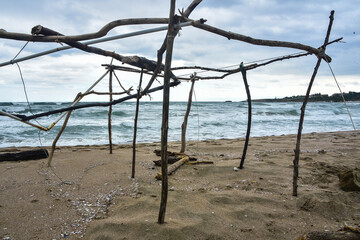 a primitive structure destroyed by bad weather on the seashore; an abstract view of the resulting...