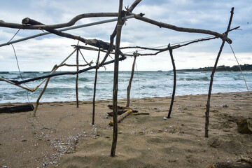 a primitive structure destroyed by bad weather on the seashore; an abstract view of the resulting structure