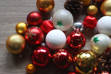 Pine cones and red, golden and white Christmas ornaments on wooden background. Selective focus.