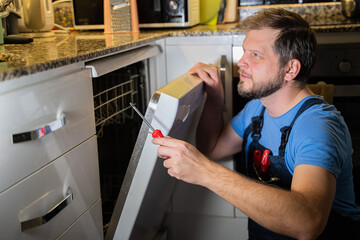 man a repairman from the service repairs the dishwasher at home