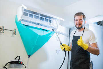 man worker from the cleaning service cleans the air conditioner at home