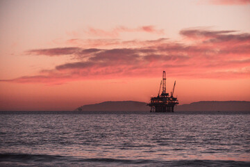 Fototapeta na wymiar oil rig at sunset beach