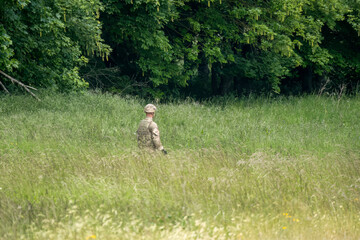 British army soldier walking through a long grass field