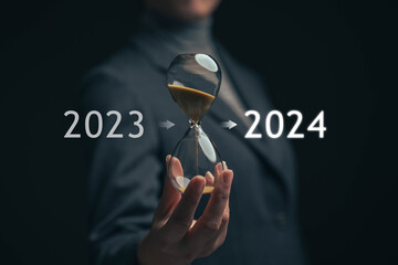 Sand clock on the hands of a businessman. The beginning of a new year. The end of 2023 and the...