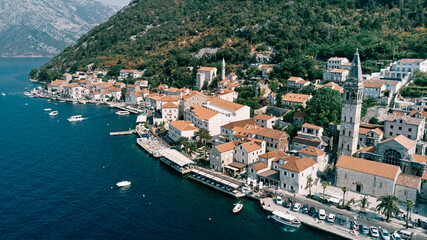 Cars are parked on the promenade near the Church of St. Nicholas. Perast, Montenegro. Drone
