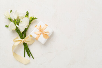 Gift box with fresia flower concrete background, top view