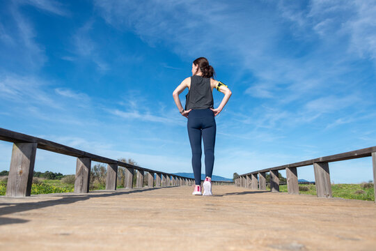 Sporty woman on a wooden boardwalk getting ready to run, rear view